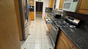 A kitchen with wooden cabinets, a stainless steel refrigerator, a microwave, and a gas stove. - Big, Serene, Central, Perfect LA (Los Angeles)
