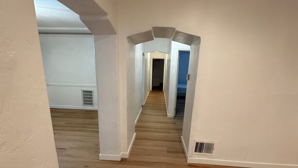 A spacious hallway with wooden flooring and white walls, leading to multiple rooms. - Big, Serene, Central, Perfect LA (Los Angeles)