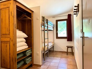 Ein Schlafzimmer mit einem Holzschrank, einem Etagenbett und einem kleinen Hocker.