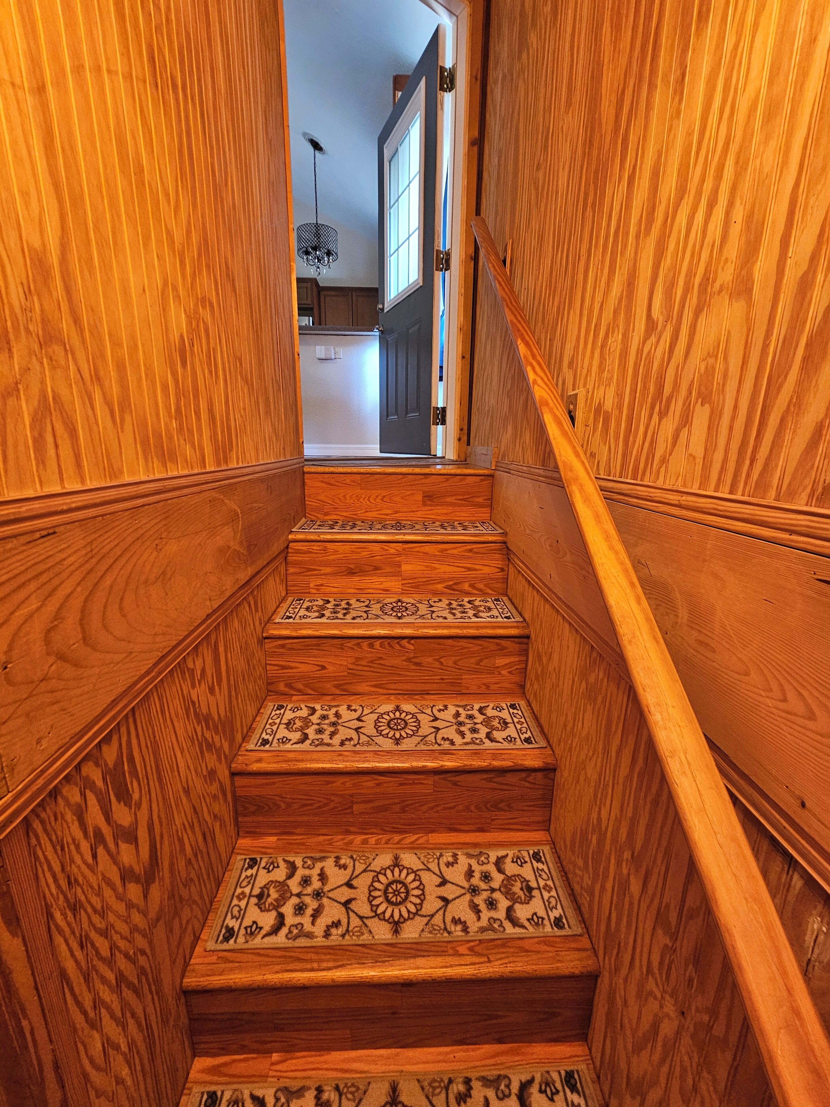 Eine Holztreppe mit gemusterten Stufen, die zu einem Raum führt.