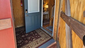 Un intérieur en bois avec une porte bleue, un extincteur et un tapis à motifs.