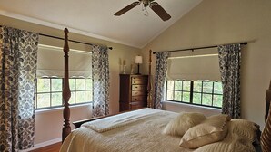 Une chambre à coucher avec un lit à baldaquin, un ventilateur de plafond et une commode.