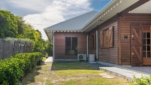 Una casa di legno con veranda coperta, tetto in metallo e un piccolo giardino con vialetto.