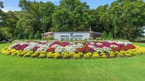 Señal de un club de golf y campo con un jardín paisajístico al frente.