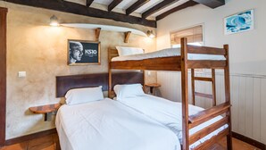A bunk bed room with a wooden headboard, a small bedside table, a poster on the wall, and a window with blinds.