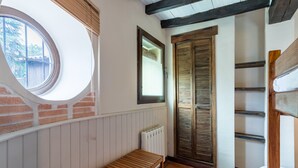 A room with a wooden bench, a window, a radiator, and a door with shutters.