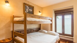 A bunk bed with a wooden headboard, a bedside table, and a window with a view. - Casa Del Surf Somo: Room 6 (Somo)