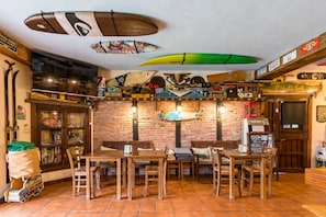 A surf-themed restaurant with surfboards on the wall, wooden furniture, and a brick wall. - Casa Del Surf Somo: Room 6 (Somo)