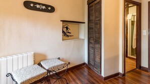 A room with a radiator, two patterned chairs, a skateboard decal, a surfboard decal, and a wooden door. - Casa Del Surf Somo: Room 5 (Somo)