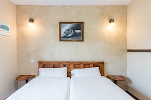 A double bed with wooden headboard, two bedside tables, and wall-mounted light fixtures.