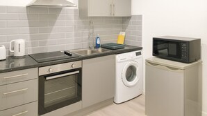 A compact kitchen with a built-in oven, a microwave, a washing machine, and a kettle. - James Lodge Rishton (Rishton)