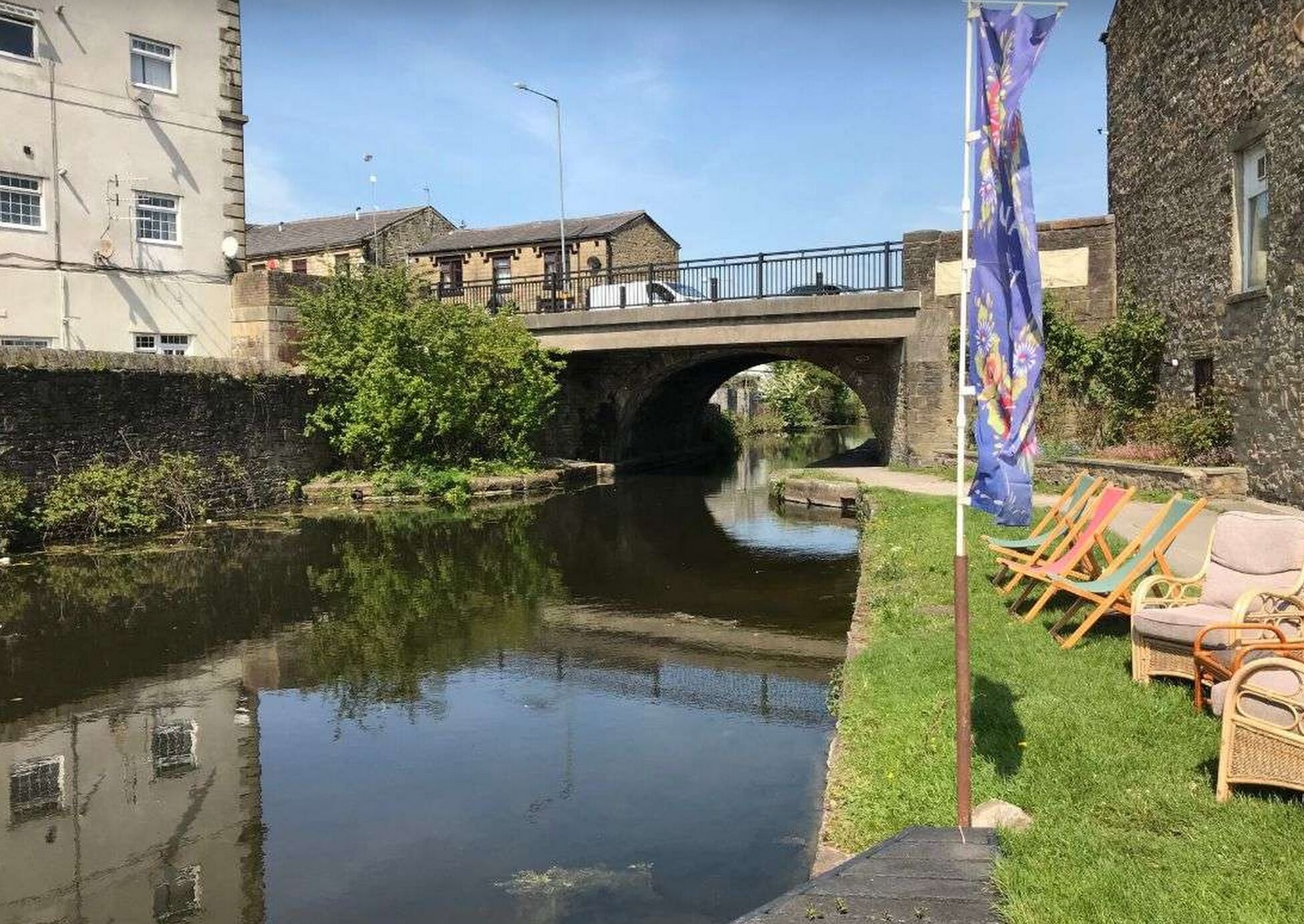 Un canale con un ponte, una bandiera e posti a sedere all'aperto.