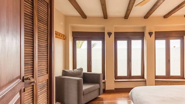 Una habitación con techo de madera, ventilador de techo, sofá, cama y ventanas grandes con vistas.