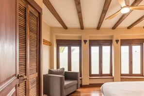 Une pièce avec un plafond en bois, un ventilateur de plafond, un canapé, un lit et de grandes fenêtres donnant sur un beau paysage.
