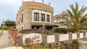 Un edificio de piedra con fachada curva, un letrero que dice 'del Surf' y una palmera en primer plano.