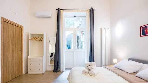 Un dormitorio con cama, armario, closet y ventana con cortinas.