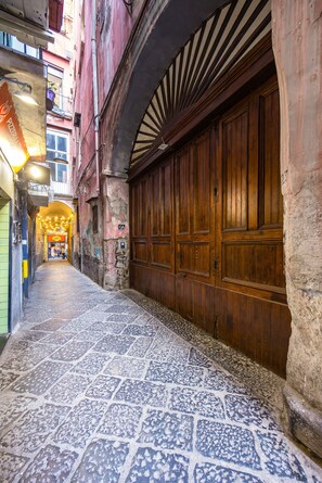 Un estrecho callejón con un sendero de adoquines, puertas de madera y un edificio de fachada de piedra.