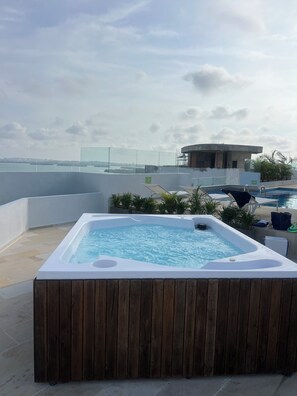 A rooftop pool area with a hot tub, lounge chairs, and a view of the city skyline. - Oceani Towers 1006 (Cartagena)