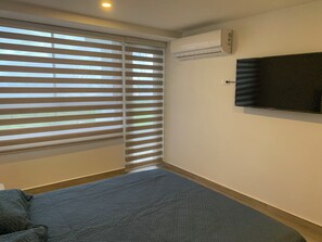 A bedroom with a bed, a TV mounted on the wall, and an air conditioning unit. - Oceani Towers 1006 (Cartagena)