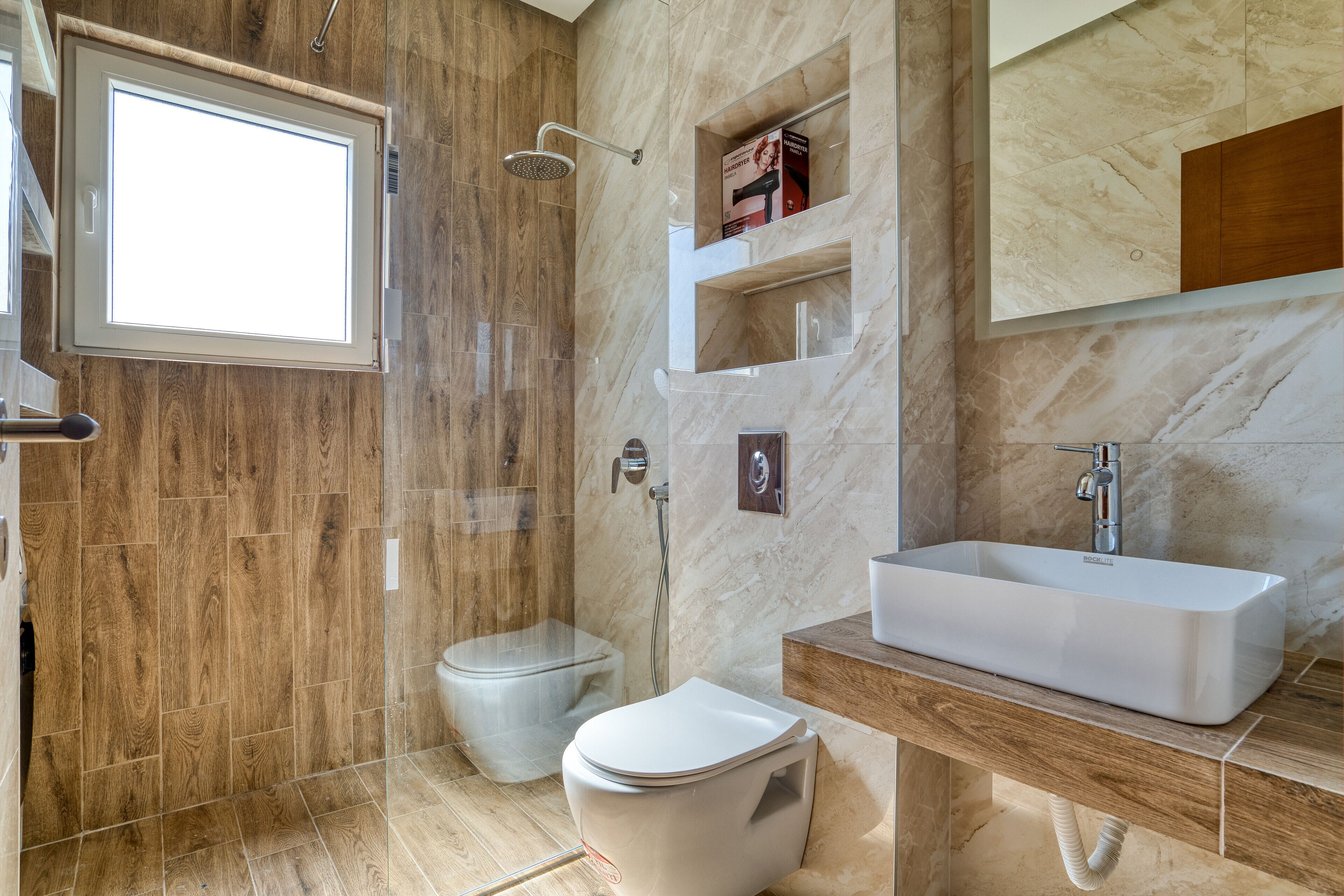 Een moderne badkamer met een douche, toilet en wastafel.