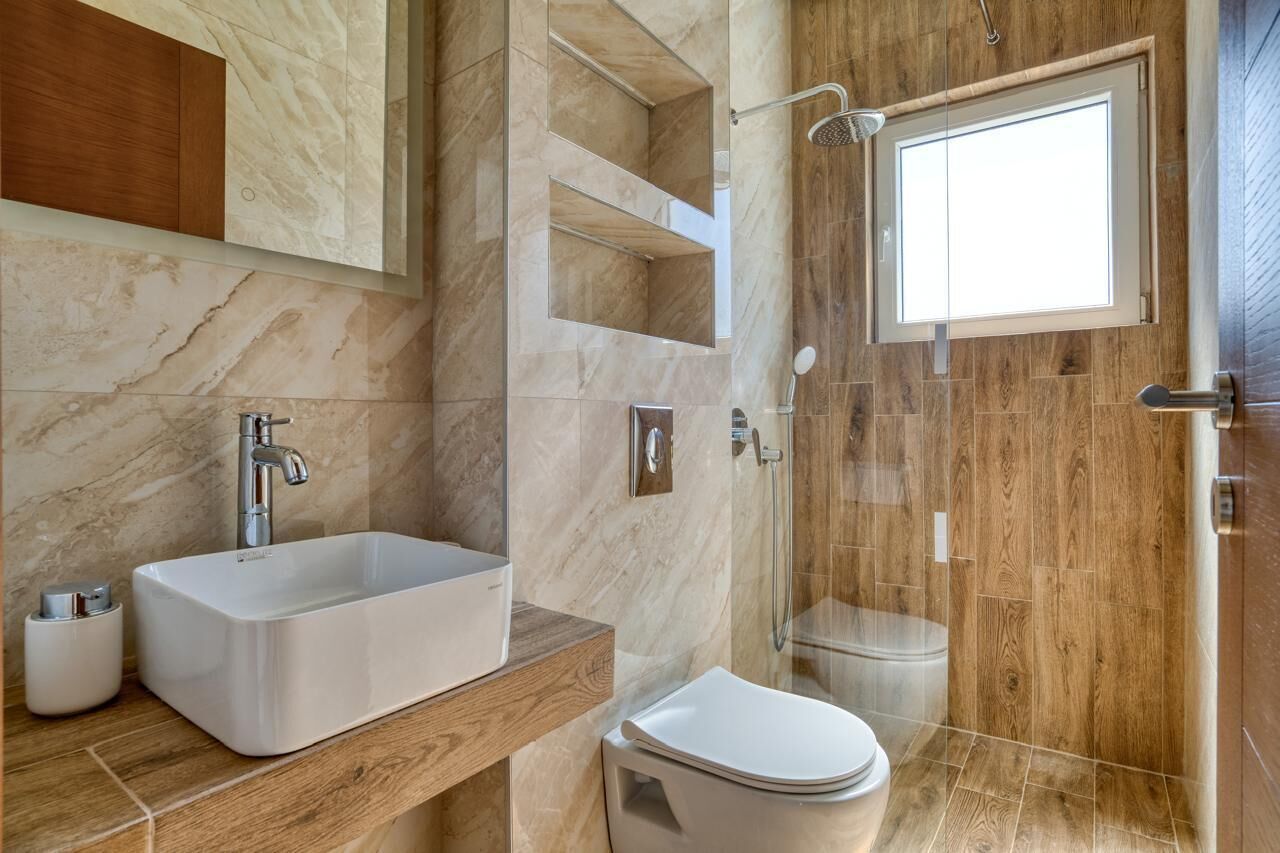 Un baño moderno con un lavamanos rectangular grande, un inodoro y una zona de ducha con cerramiento de vidrio.