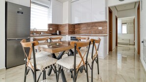 A modern kitchen with a stainless steel refrigerator, wooden dining table, and chairs, featuring a clean, minimalist design. - Apartments Ljubica  (Denovici)