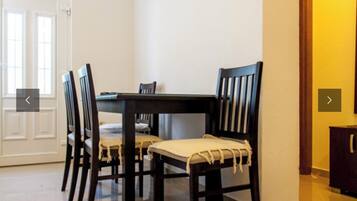 A dining area with a dark wooden table and four chairs, each with a light-colored cushion.