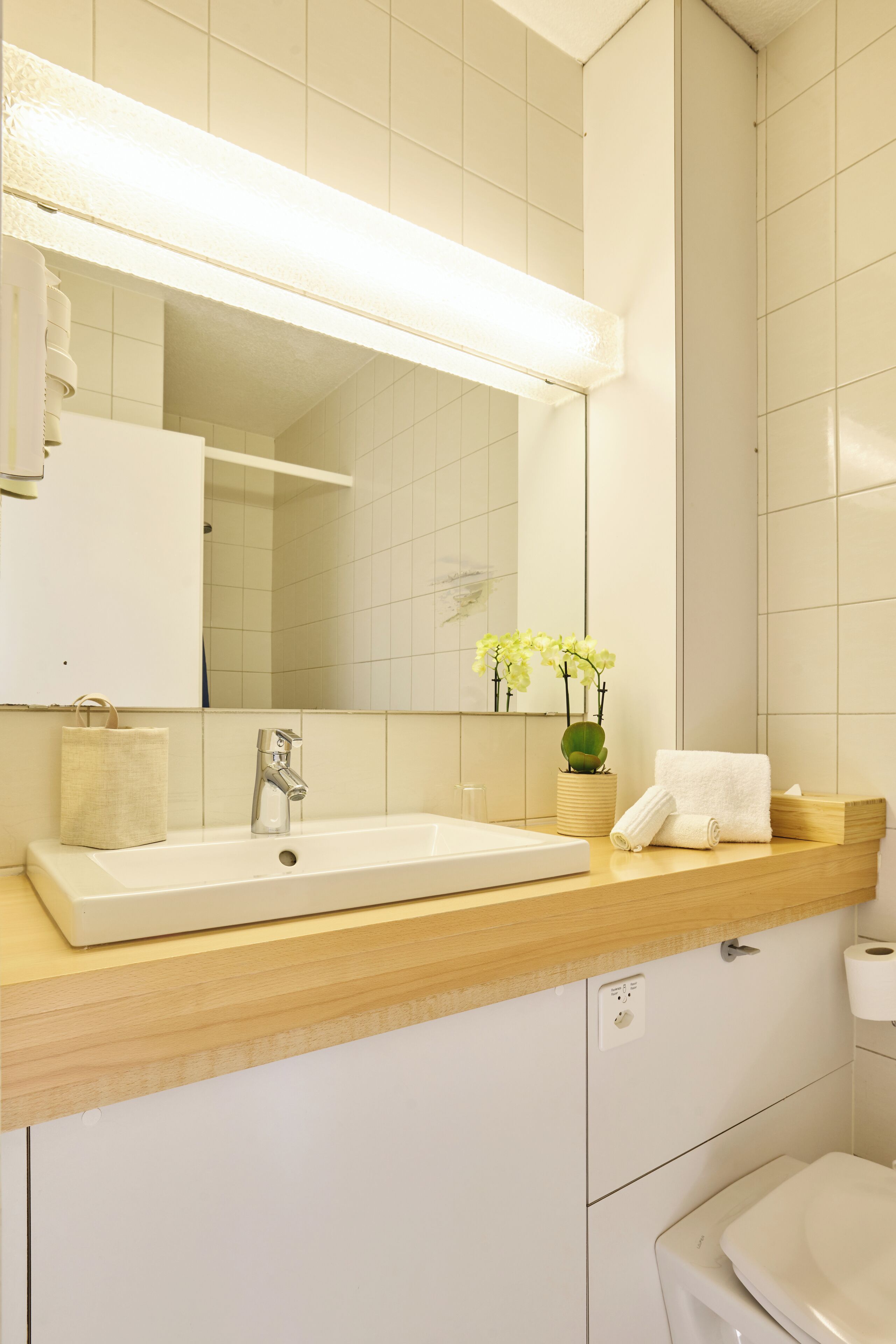 A bathroom with a white sink, mirror, and toilet.