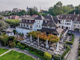 A hotel with a terrace, outdoor seating, and a flag.