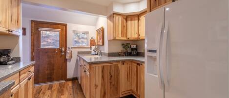 Eine Küche mit Holzausstattung, einem weißen Kühlschrank und einer Arbeitsplatte aus Granit.