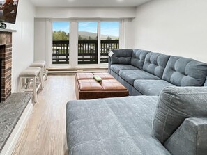 Una sala de estar moderna con un sofá seccional gris, un banco de madera y una mesita.