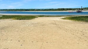 A sandy beach with a clear blue sky and calm water. - Admiral's Quarters (Wells)