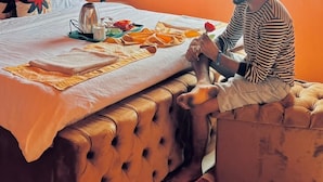 A room with a bed, a window, and a person sitting on the bed.