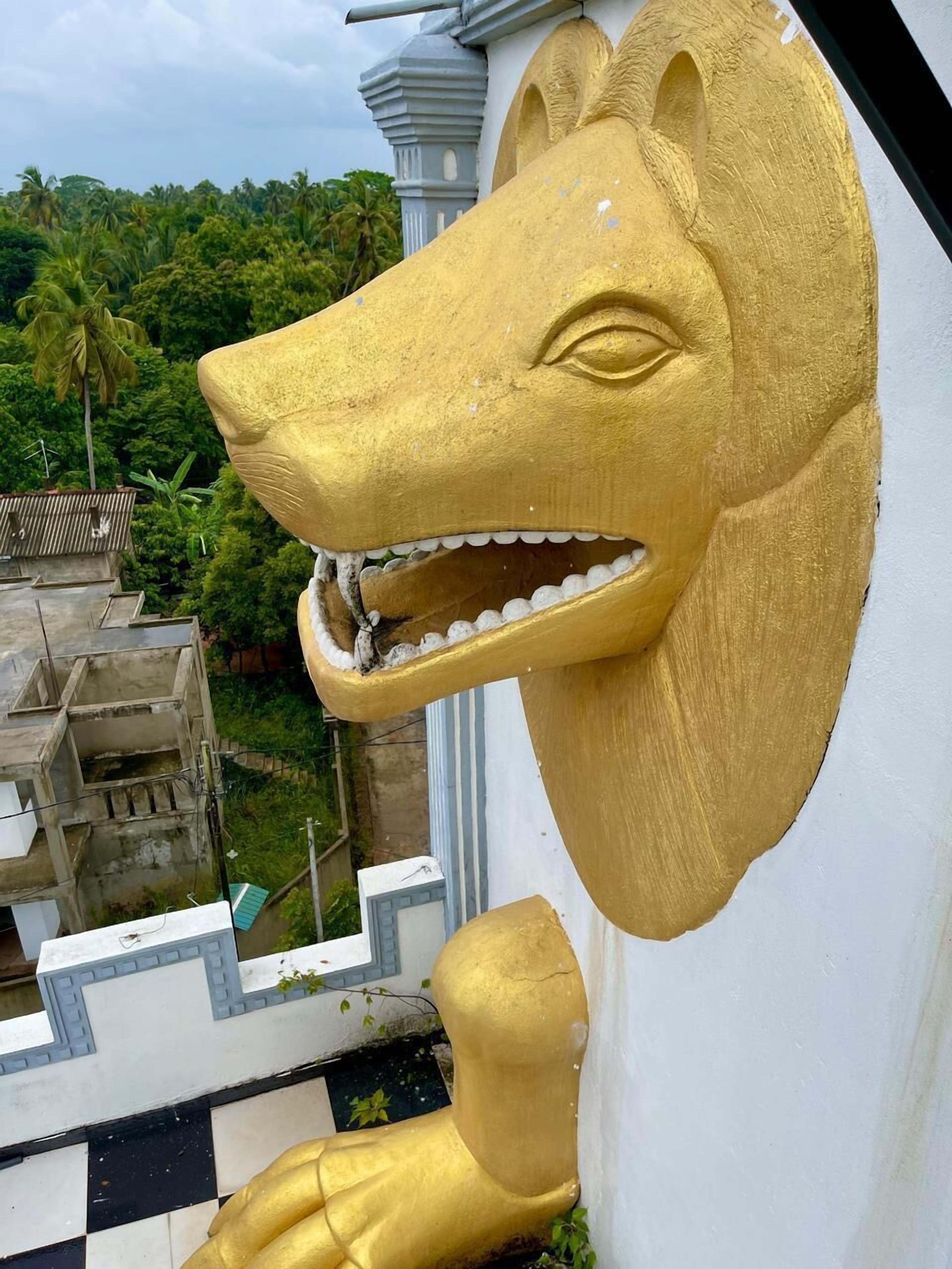 Une sculpture représentant une tête de lion en or, fixée à un bâtiment.