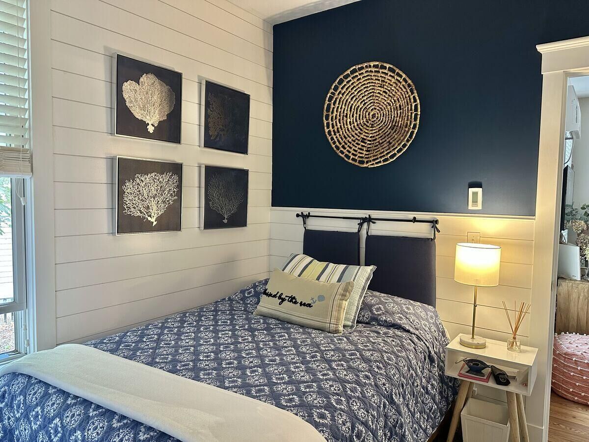 A bedroom with a bed, a bedside table with a lamp, and wall art.