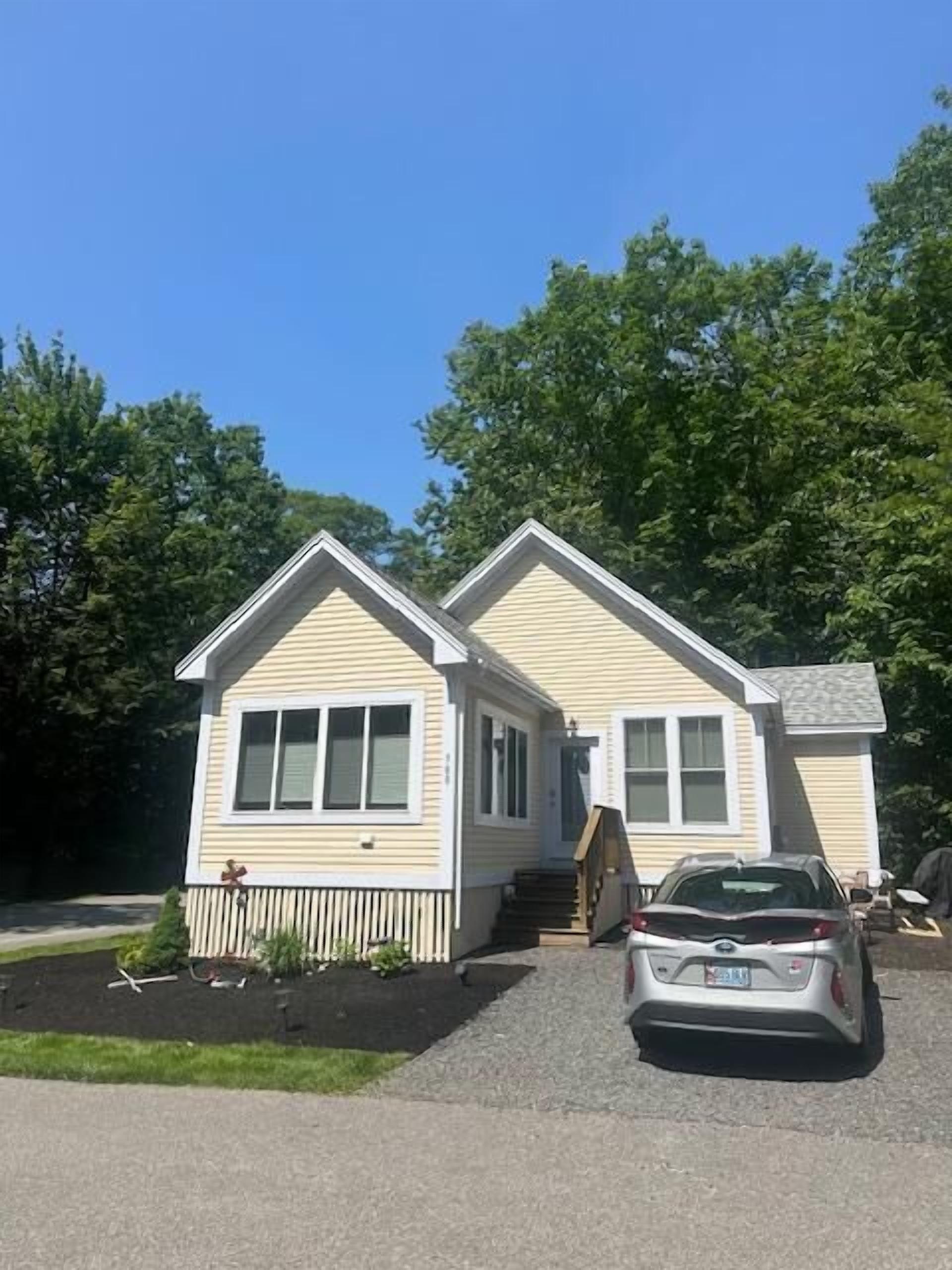 A two-story house with a front porch, a car parked in front, and a well-maintained lawn.