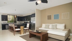 Ein modernes Wohnzimmer mit Sofa, Couchtisch und Essbereich mit Stühlen und einem Holzbalken.