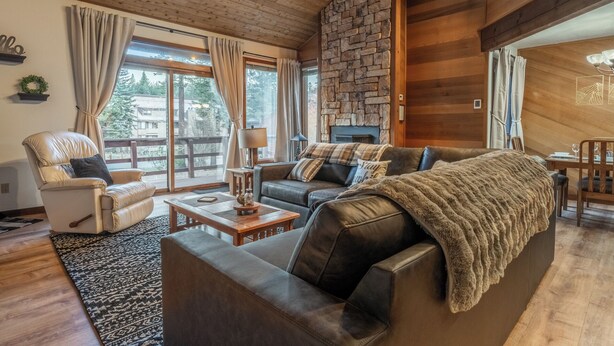 A cozy living room with a stone fireplace, leather sofas, and a dining area with wooden furniture. - Hogans Hideaway  639 (Mammoth lakes)