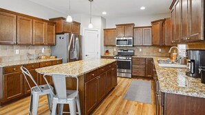 A modern kitchen with wooden cabinets, granite countertops, stainless steel appliances, and pendant lighting. - 300 on Abigail. 
4BR/3BA. Large kitchen. Deck with TV. Playground. (Waukee)