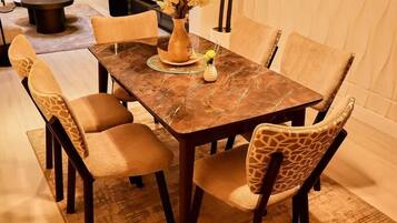 A dining area with a rectangular table, six chairs, and a vase with dried flowers.