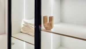 A modern, well-lit room with a glass partition, white shelves, and neatly folded towels. - Purple Lavender Court Apartment (Lagos)