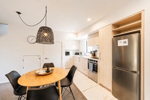Eine moderne Küche mit einem Edelstahl-Kühlschrank, Holzschränken und einem Essbereich mit rundem Tisch und Stühlen.