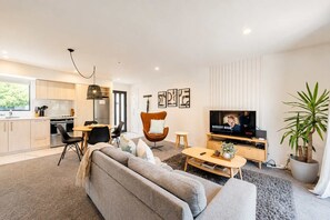 Un salon moderne comprenant un canapé, un téléviseur et un coin repas avec des chaises et une table.