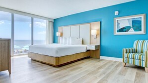 Ein Hotelzimmer mit einem großen Bett, Meerblick und einer blauen Akzentwand.