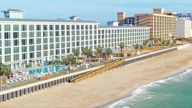 Ein modernes Hotel mit großzügiger Poolanlage, Strandlage und Blick auf den Ozean.