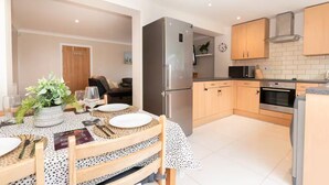 Une cuisine moderne dotée d’appareils électroménagers en acier inoxydable, de meubles en bois et d’un coin repas avec une table dressée pour deux personnes.