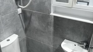 Un bany modern amb vàter, rentapel i plat de dutxa.