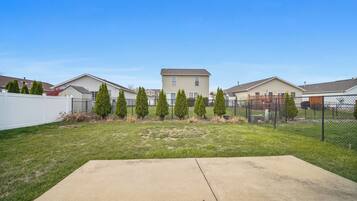 A residential area with houses, a fenced yard, and a concrete patio.