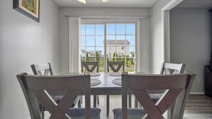 A dining area with a table and chairs, a window with a view of houses, and a ceiling light fixture. - Grey Moon Escape In Bloomington (Bloomington)