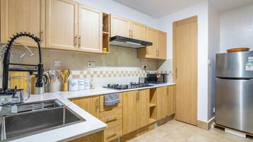 A kitchen with wooden cabinets, a stainless steel refrigerator, a gas stove, and a sink.